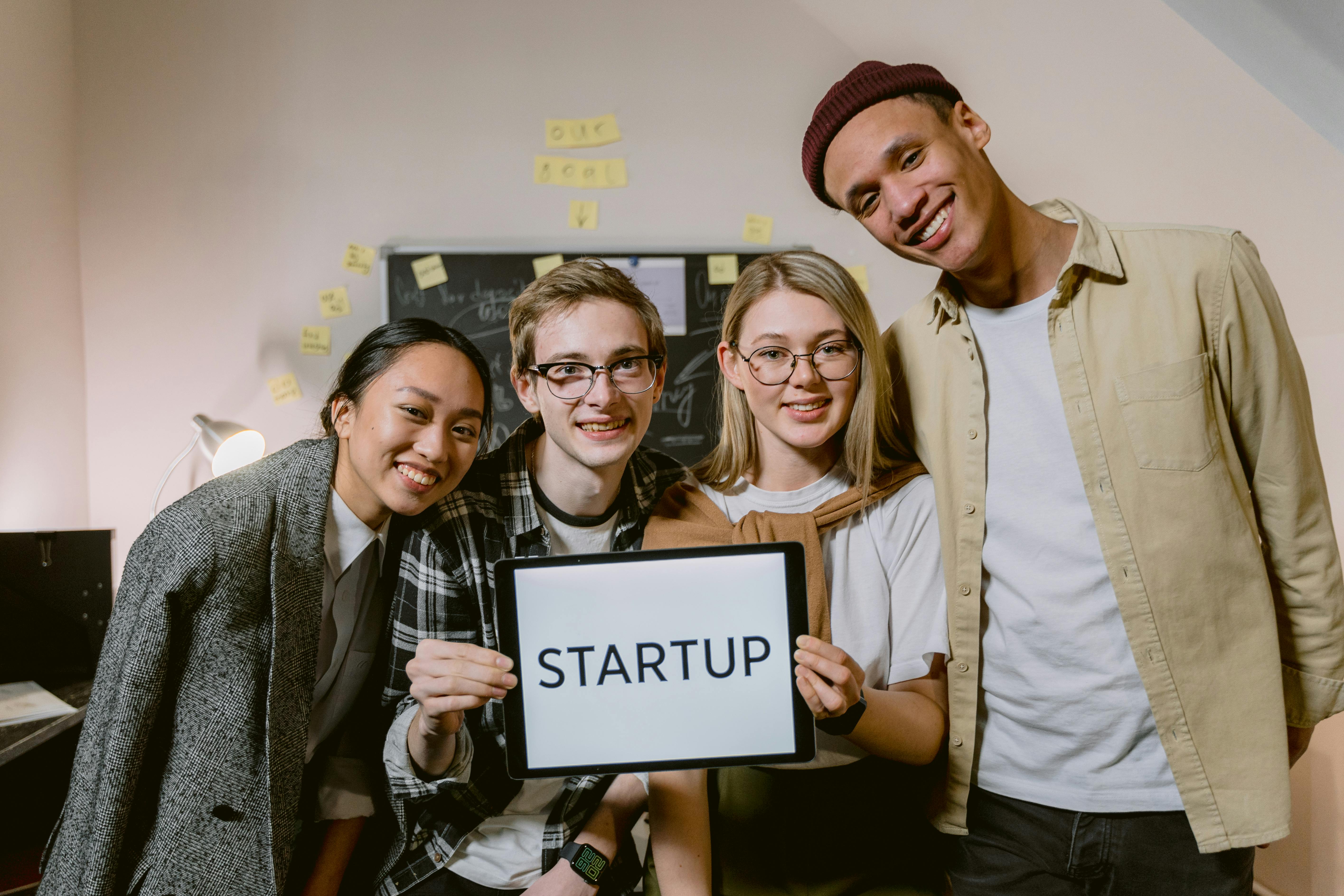 Free A diverse group of young professionals in a startup office, smiling and holding a sign. Stock Photo